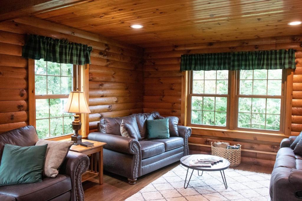 a living room with couches and windows in a log cabin at Maple Leaf Cabin in Millersburg