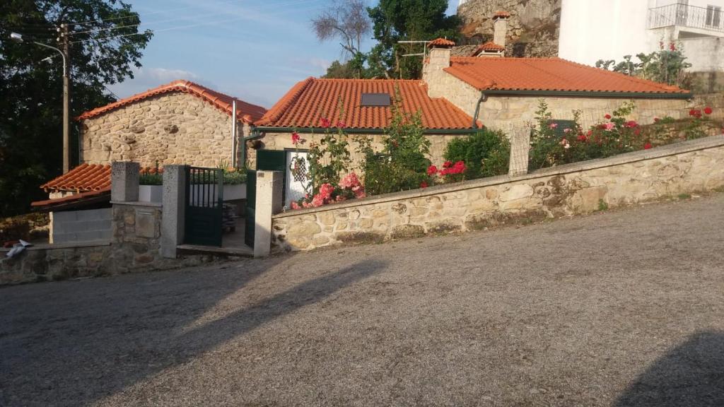 a house with a stone fence next to a street at Casa dos Telhados 