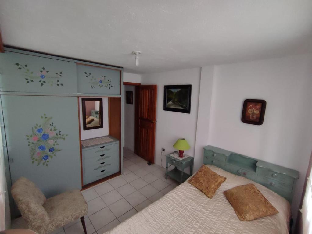 a bedroom with a bed and a chair and a dresser at Casa galería de arte in Quito