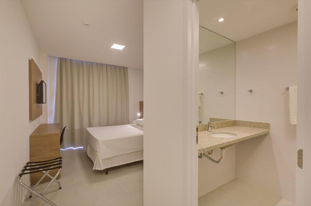 a bathroom with a bed and a sink and a mirror at Go Inn São Mateus in São Mateus