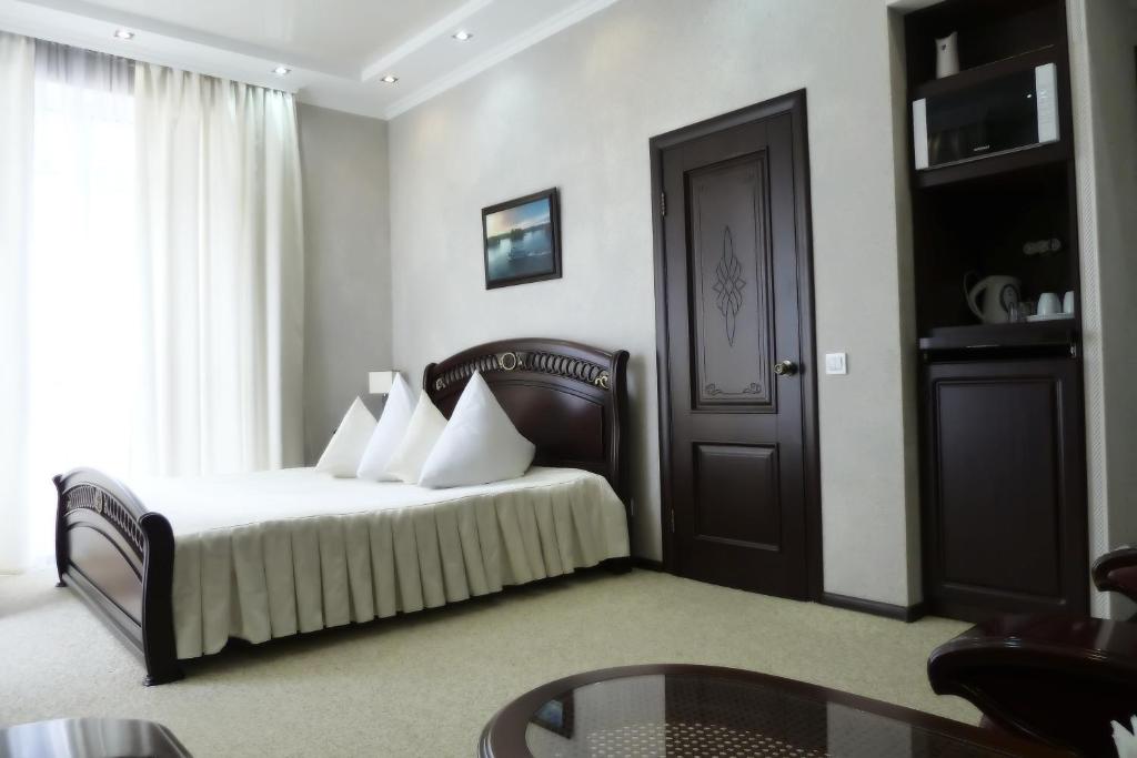 a bedroom with a bed with white pillows and a table at Guest Rooms in Park-Hotel in Sevastopol