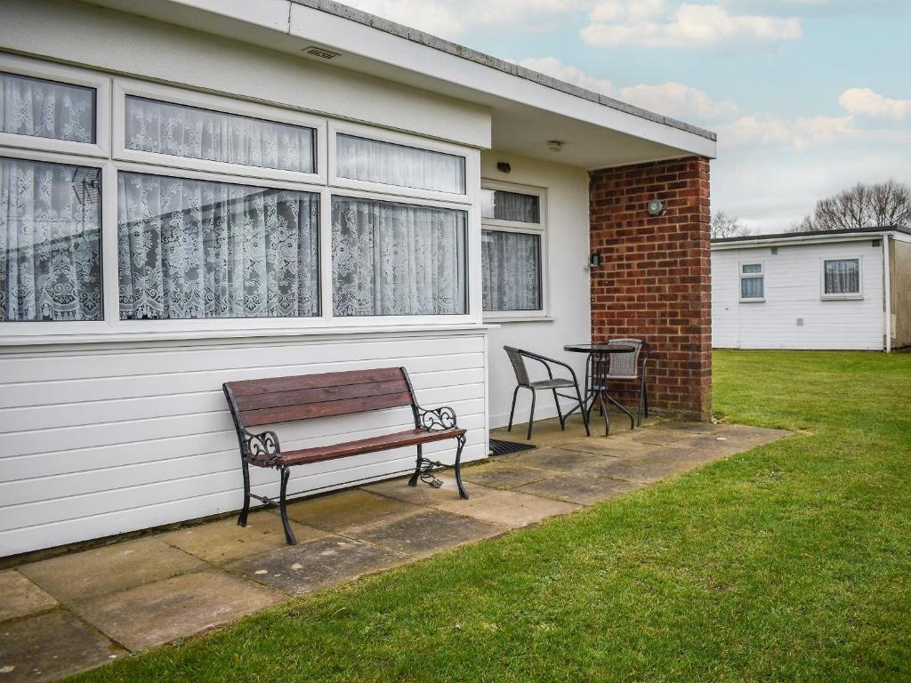 un banc assis à l'extérieur d'une maison avec une table dans l'établissement Sandy Toes, à Scratby