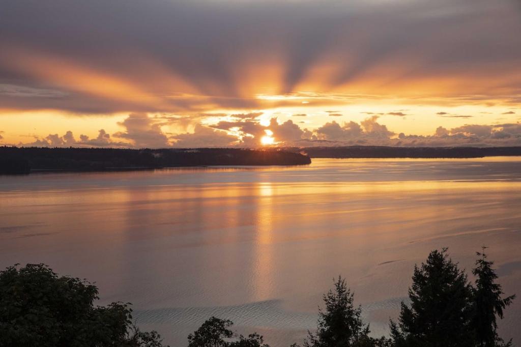 um pôr-do-sol sobre uma grande massa de água em 180º Puget Sound View em Fox Island
