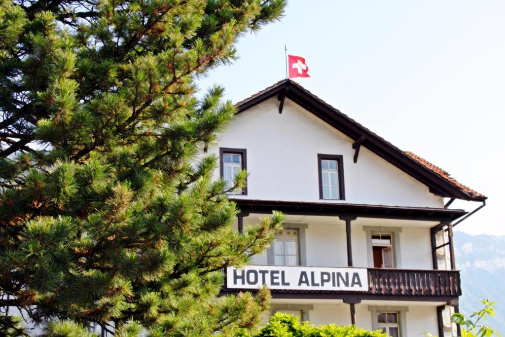 a building with a sign in front of a pine tree at Alpina Hotel in Interlaken