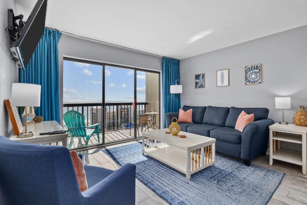 a living room with blue furniture and a balcony at Cottage By the Sea! Renovated Condo with Ocean Views! in Myrtle Beach