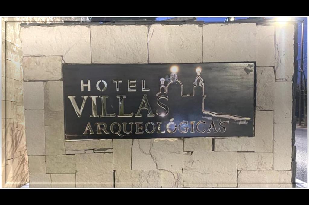 un cartello su un muro di mattoni con un cartello delle ville d'hotel di Villas Arqueologicas Cholula a Cholula