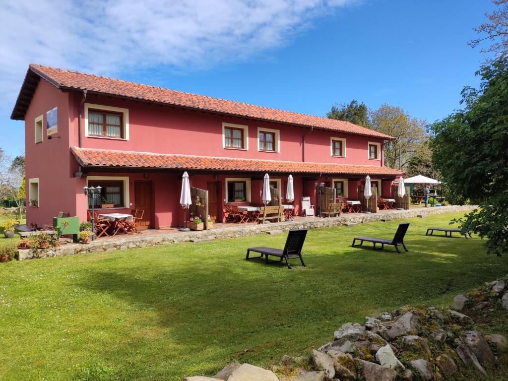 a red house with benches in a yard at Apartamentos Rurales Llagumelon in Villahormes
