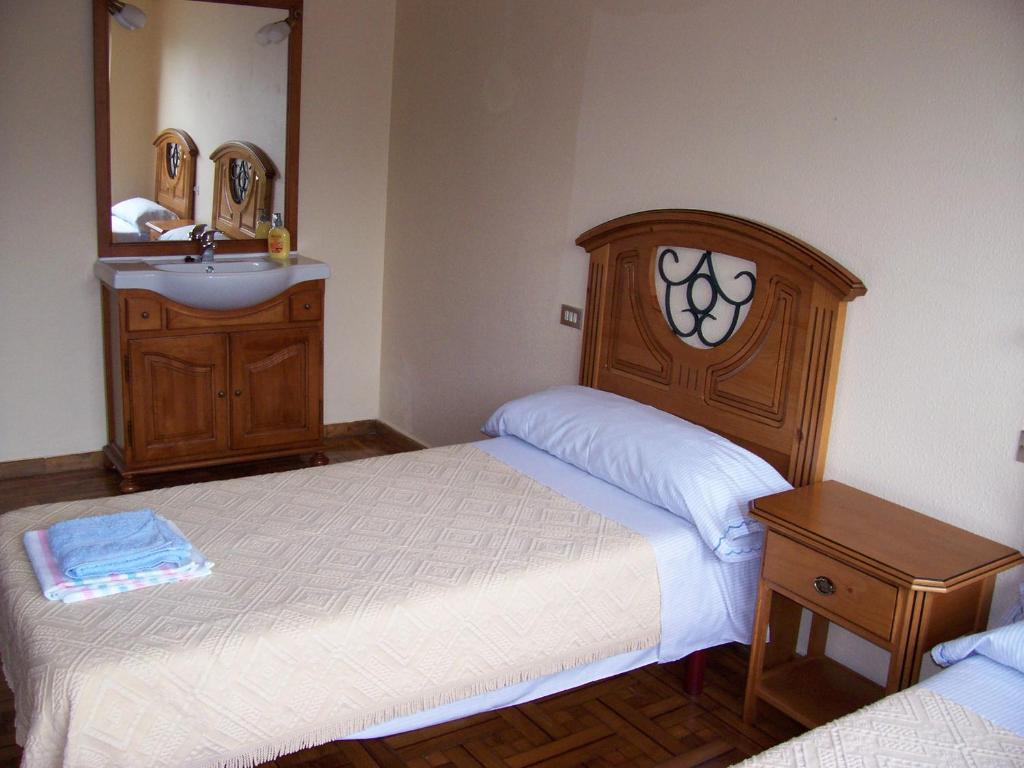 a bedroom with two beds and a sink and a mirror at Pensión ** Abacá Gijón in Gijón