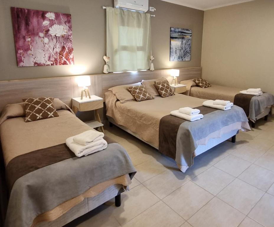 um quarto de hotel com três camas e duas mesas em Casas Noviembre em Plottier