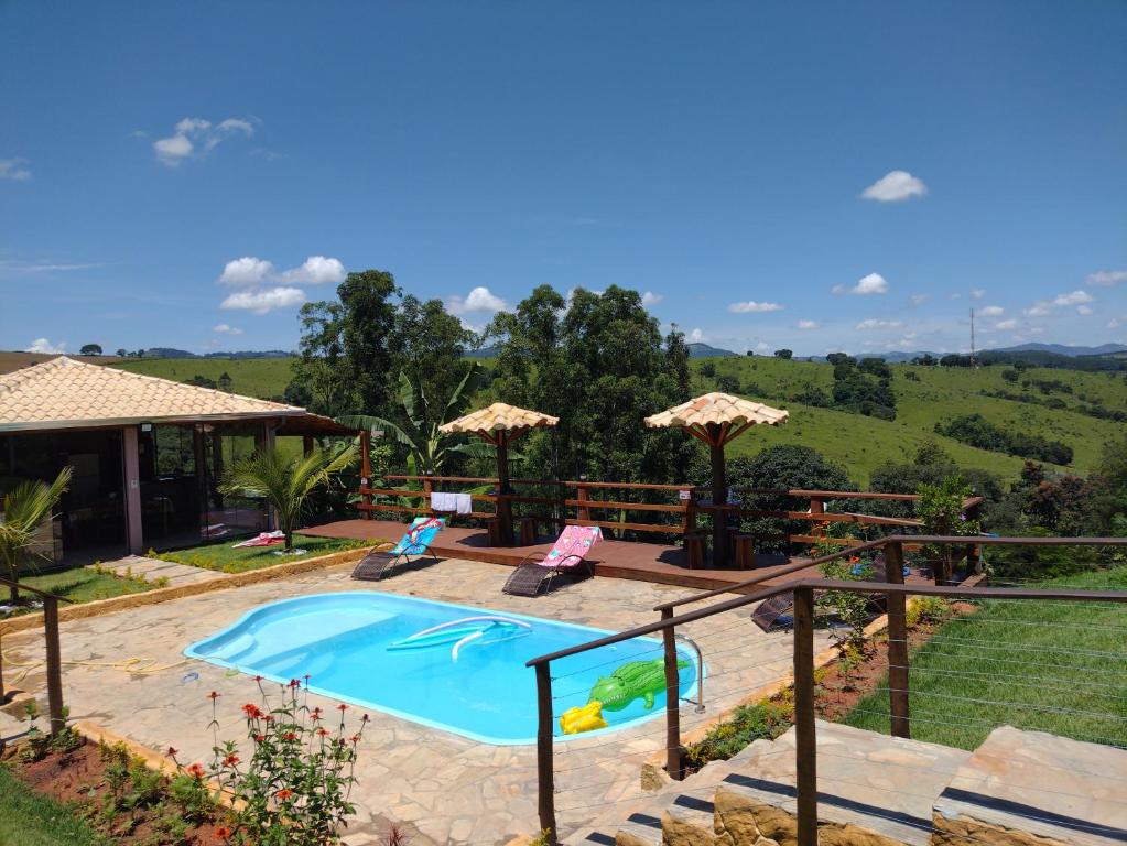 a swimming pool in a yard with two chairs at Chácara Jerusalém in Lindóia