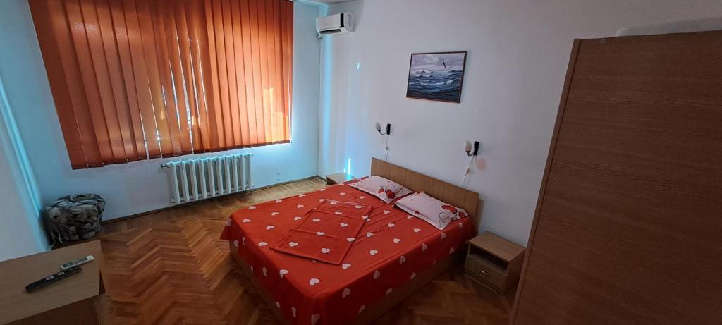 a bedroom with a bed with a red comforter and a window at Apartament Grigore Etaj 2 in Mangalia