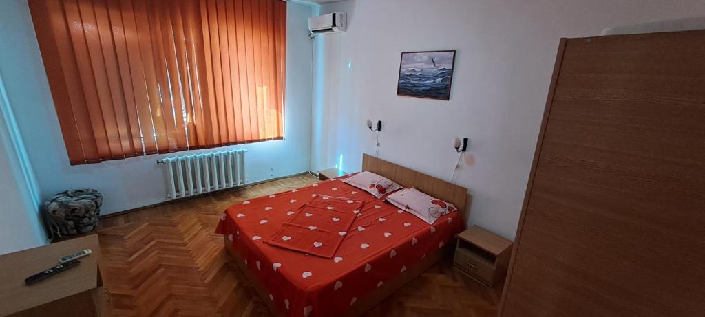 a bedroom with a bed with a red comforter and a window at Apartament DR in Mangalia