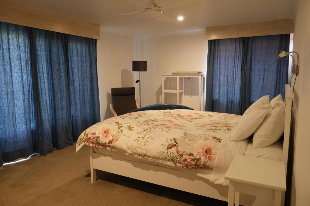 a bedroom with a large bed with blue curtains at Twodogfolly at Creeklands in Armidale