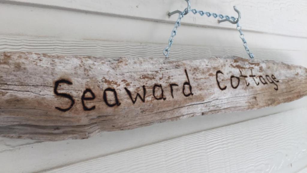 un cartel que lee café hacia el mar colgando de una puerta en Seaward Cottage, Nelly Bay, en Nelly Bay