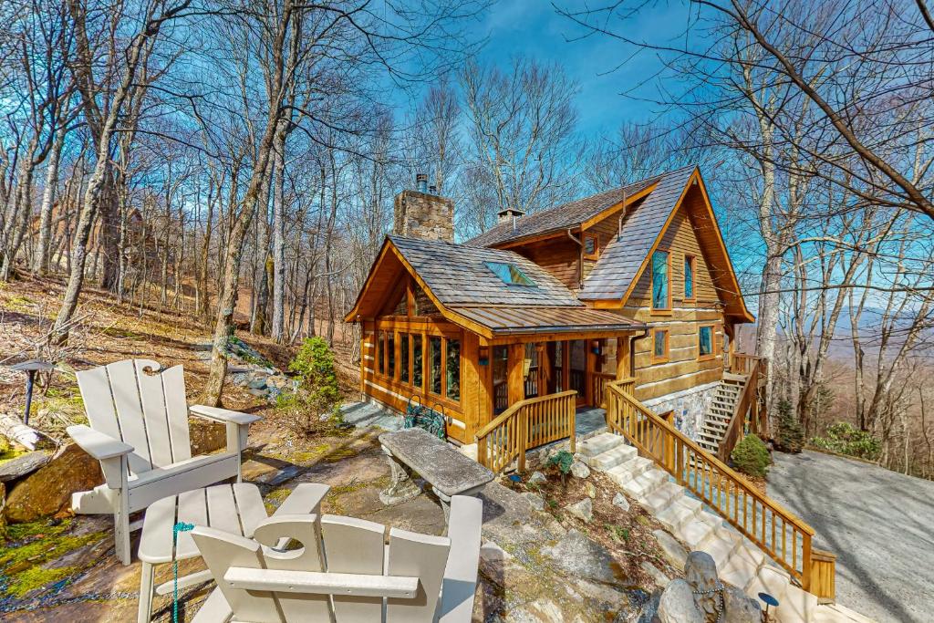 a log cabin in the woods with a group of chairs at Rocksway Cabin in Banner Elk