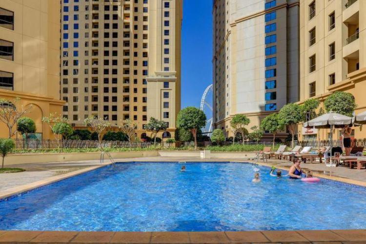 a woman sitting in a swimming pool in a city at The beach hostel Dubai in Dubai