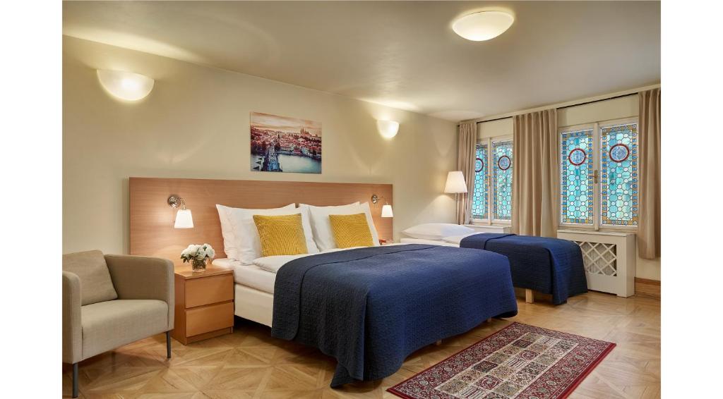 1 dormitorio con 2 camas, silla y ventanas en Mostecká 12 Residence, en Praga