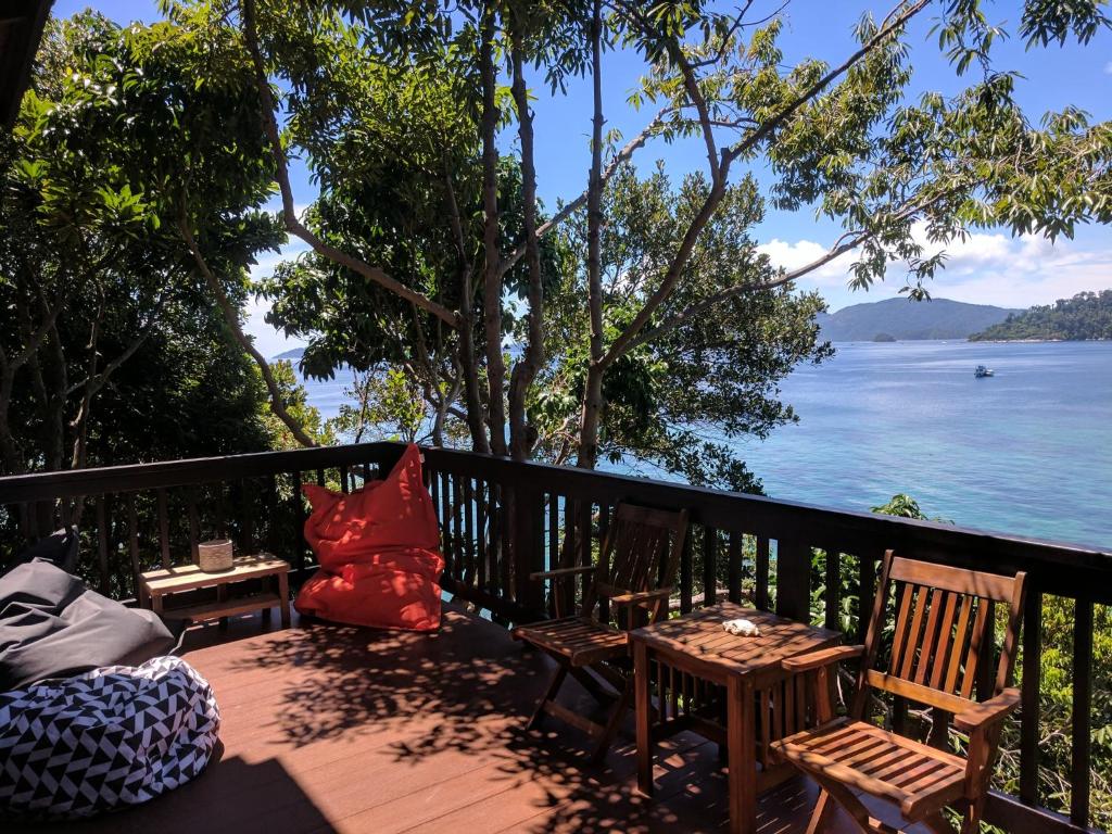 balcón con sillas, mesas y vistas al agua en Cashewnut Cove en Ko Lipe