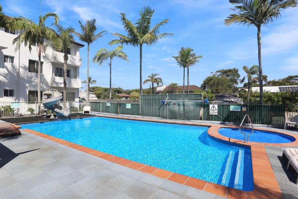 a swimming pool with palm trees and a building at Providence Apartment 3 in Hawks Nest