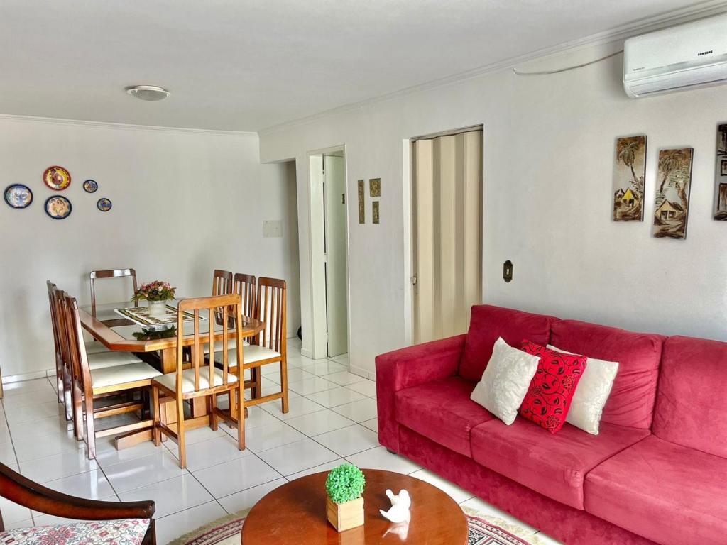 sala de estar con sofá rojo y mesa en Apto espaçoso uma quadra do mar com garagem, en Balneário Camboriú
