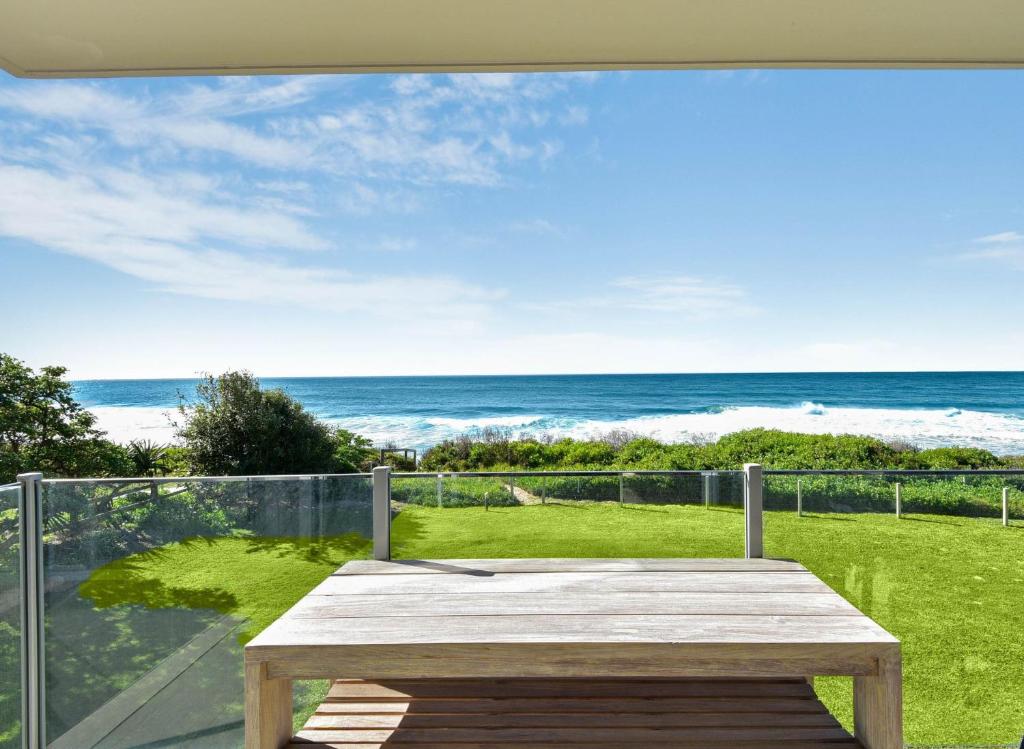 a wooden table on a balcony with a view of the ocean at Regency Court Absolute Beachfront in The Entrance