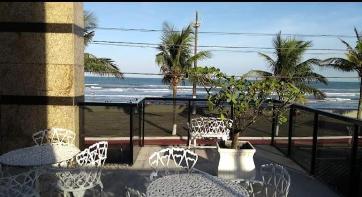 a balcony with tables and chairs and the beach at apartamento pé na areia Mongaguá in Itanhaém