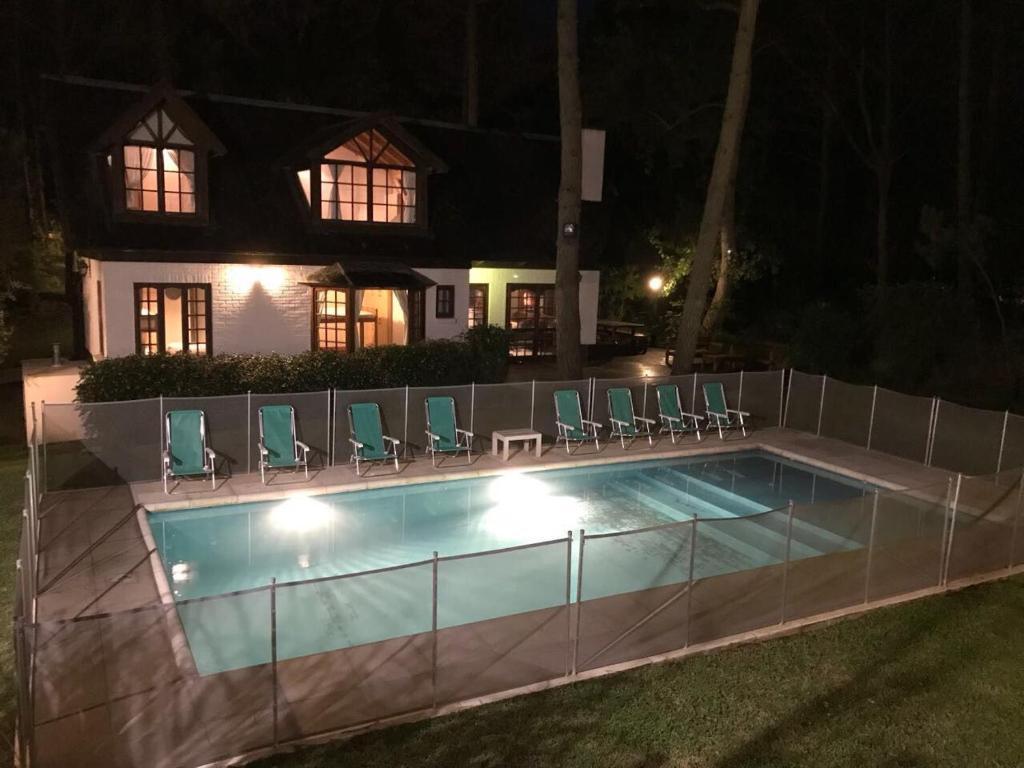 una piscina con sillas alrededor por la noche en Casa Carilo en Cariló