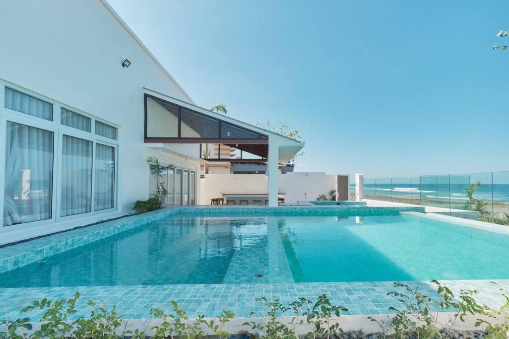 a swimming pool in front of a house with the ocean at Alesea Baroro, La Union, Private Modern Villa with Pool, Jacuzzi, Beachfront View in Balio