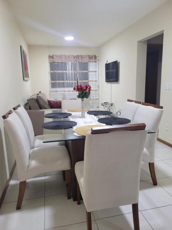 uma sala de jantar com uma mesa e cadeiras brancas em Apartamento residencial em Blumenau