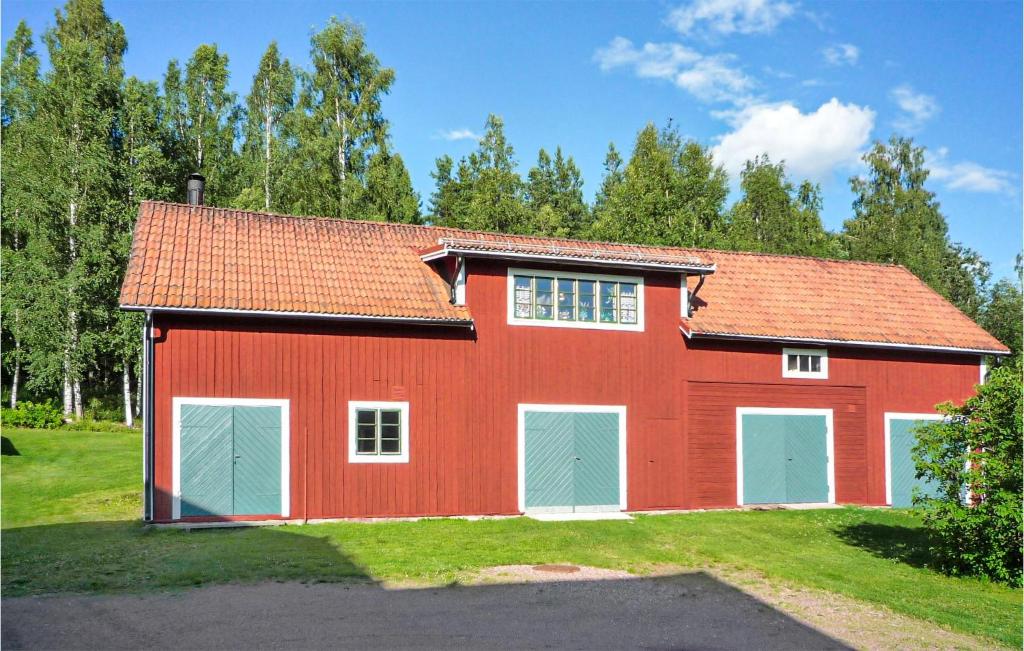a red barn with two garage doors on a field at Lovely Apartment In lvdalen With Kitchen in Älvdalen