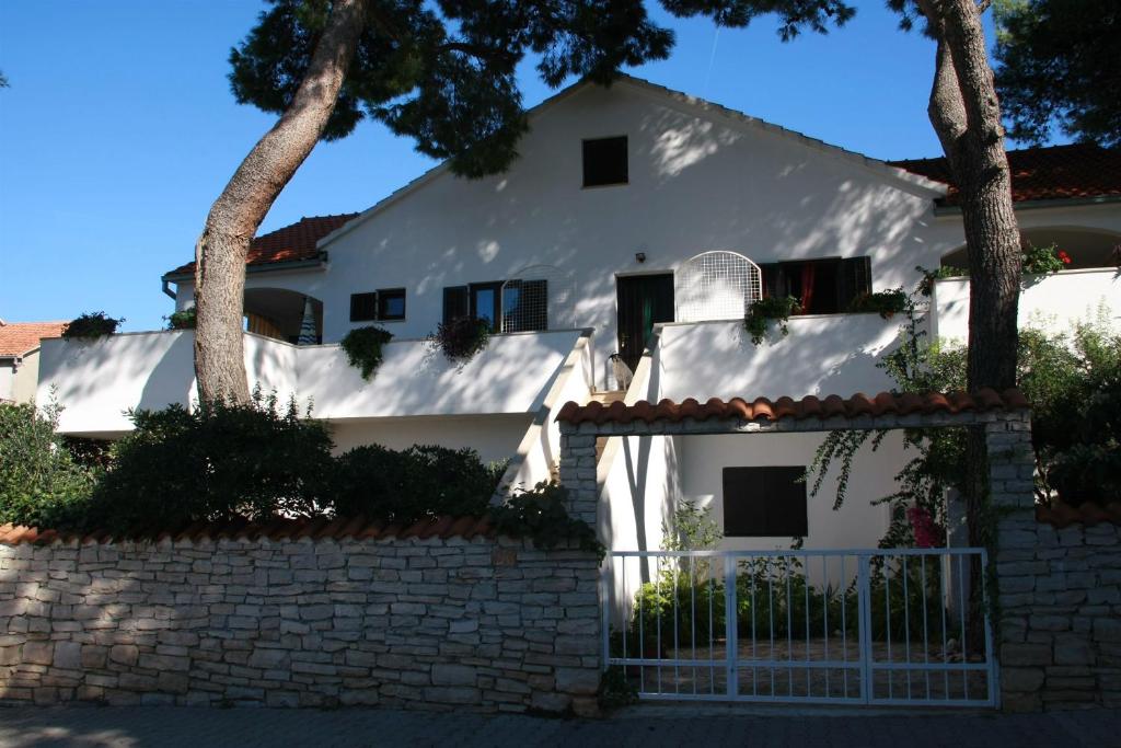uma casa branca com cerca e árvores em Apartments Frano em Mirce
