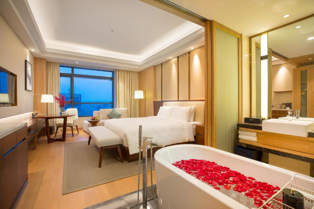 Landison Plaza HSD Hotel Hangzhou في هانغتشو: غرفة في الفندق مع سرير وحوض استحمام