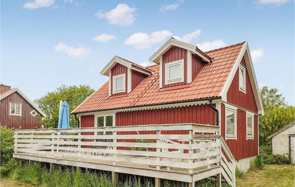 a red house with a wooden fence in front of it at Lovely Home In Degerhamn With Kitchen in Degerhamn