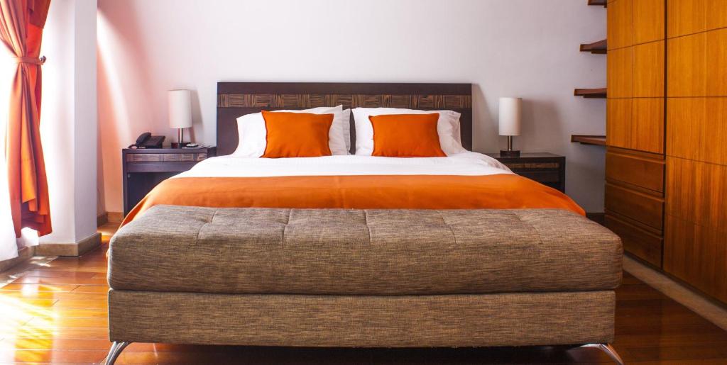 ein Schlafzimmer mit einem großen Bett mit orangefarbenen Kissen in der Unterkunft Prisma Suites Chico 94 in Bogotá