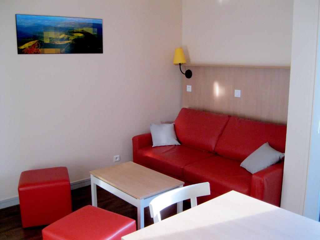 - un salon avec un canapé rouge et une table dans l'établissement VVF Super-Besse Auvergne Sancy, à Super-Besse