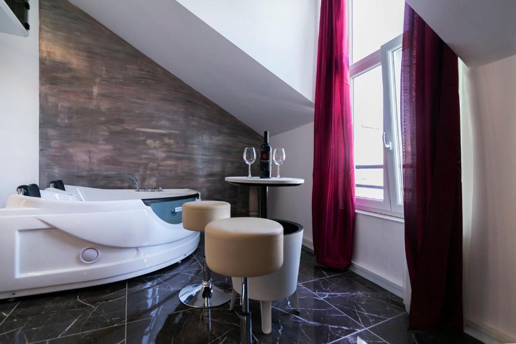 ein Bad mit einer Badewanne und einem Tisch mit Stühlen in der Unterkunft Apartments Royal 2 in Stomorska