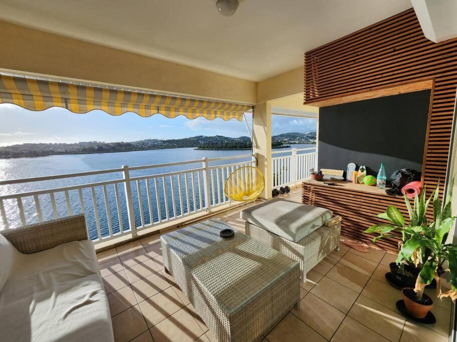 Magnifique appartement, vue mer في نومْيا: غرفة مع شرفة مطلة على الماء