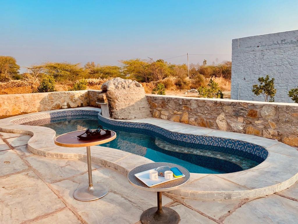 a pool with a table next to a stone wall at Jawai Wildlife Safari Camp in Nāna