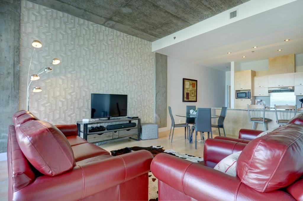 sala de estar con muebles de cuero rojo y TV de pantalla plana en Les Immeubles Charlevoix - Le 760102, en Quebec