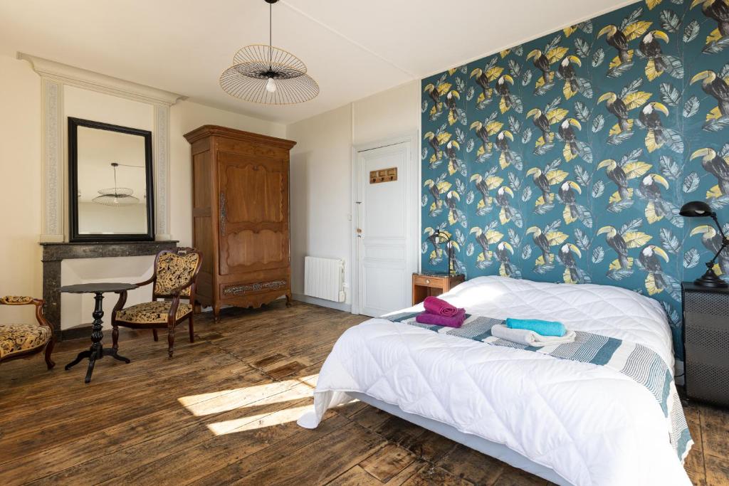 1 dormitorio con cama y pared con papel pintado de pájaro en LaConciergerieJonzac, Maison Côté Vintage avec jardin, en Jonzac
