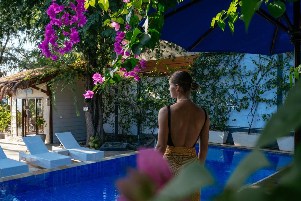 a woman in a bathing suit standing next to a swimming pool at Bale Sampan Boutique Bungalows in Gili Trawangan