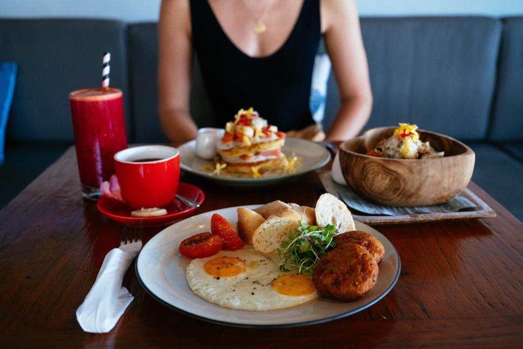 a woman sitting at a table with plates of breakfast foods at Bale Sampan Boutique Bungalows in Gili Trawangan