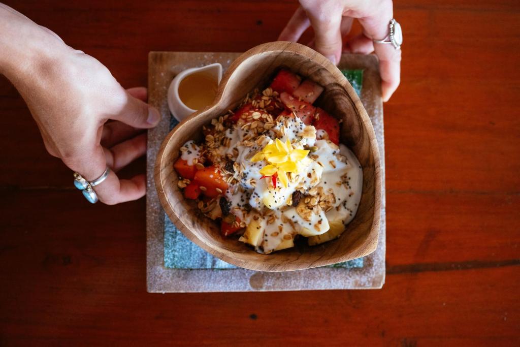 a person holding a bowl of food on a table at Bale Sampan Boutique Bungalows in Gili Trawangan