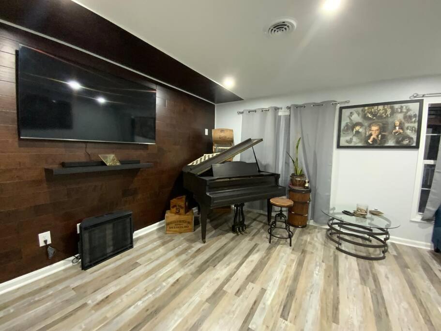 a living room with a piano and a flat screen tv at Artistic luxury home downtown/train to NYC/AirPort in Newark