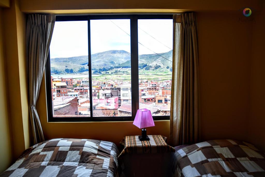 Dormitorio con ventana, cama y lámpara en solsticio hostel, en Copacabana