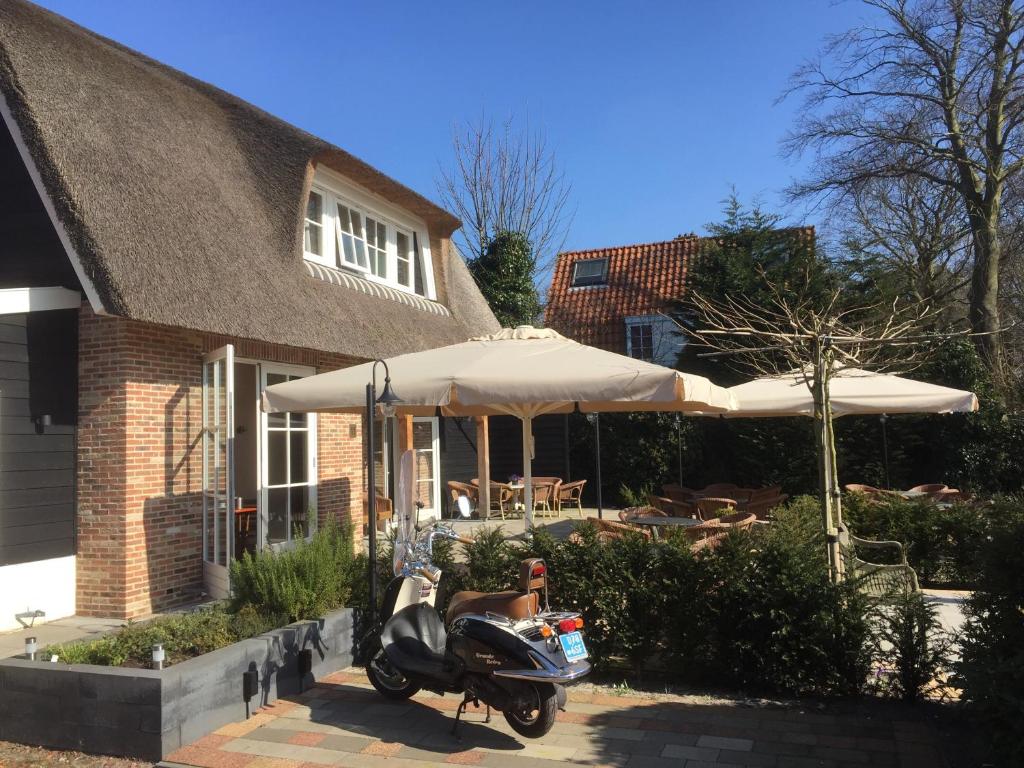 ein Roller, der vor einem Haus mit einem Regenschirm parkt in der Unterkunft Herberg het Landhuis in Schoorl