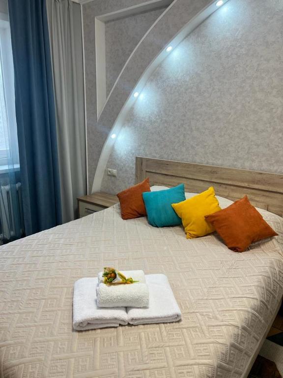 Una cama con almohadas coloridas y toallas. en Квартира бизнес класса en Semey