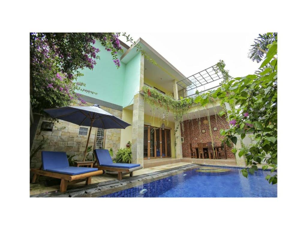 a house with a pool and two chairs and an umbrella at The Lavana Jasmine Villa in Senggigi