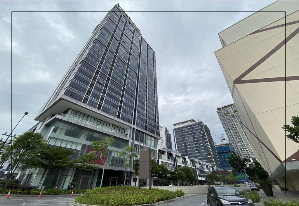 een hoog gebouw in een stad met auto's voor de deur bij Sri Murni Homestay Aurora Place Bukit Jalil in Kuala Lumpur