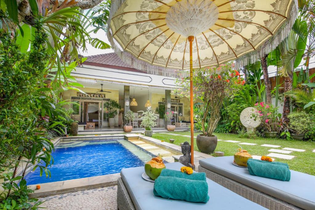 una piscina en el patio trasero de una casa con una sombrilla grande en Villa Balissima, en Seminyak